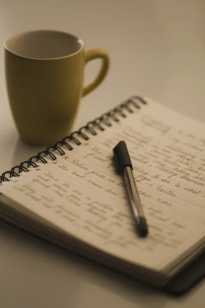 Pen on an open notebook and a coffee cup — Stock Photo, Image