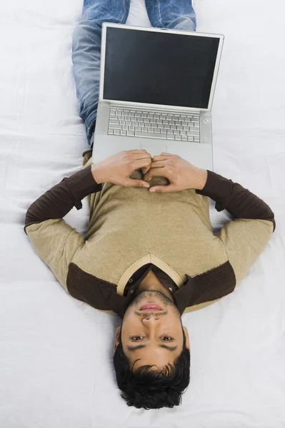 男子躺在床上，一台笔记本电脑 — 图库照片