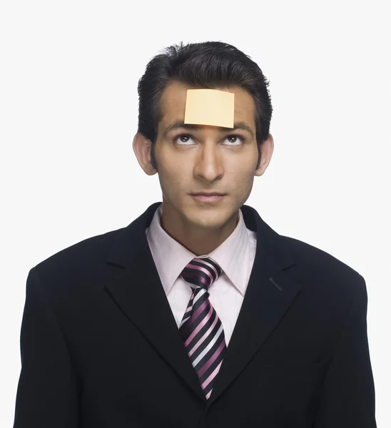 Businessman looking at a sticky note on his forehead — Stock Photo, Image