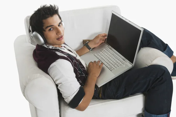 Uomo ascoltare le cuffie durante l'utilizzo di un computer portatile — Foto Stock