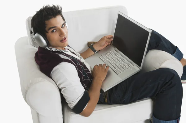 Man listening to headphones while using a laptop — Stock Photo, Image