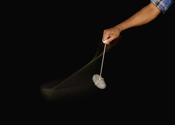 Person's hand swinging a stone pendulum — Stock Photo, Image
