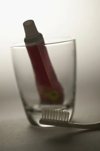 Toothbrush and a toothpaste in a glass — Stock Photo, Image