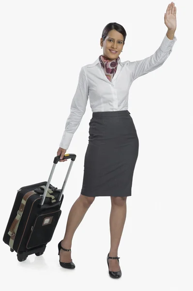 Air hostess carrying her luggage and waving — Stock Photo, Image