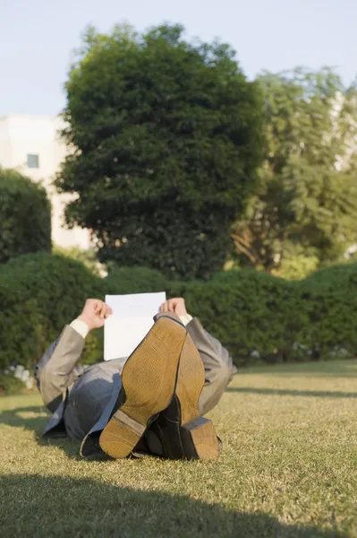 Empresário lendo um jornal em um parque — Fotografia de Stock