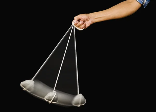 Person's hand swinging a stone pendulum — Stock Photo, Image