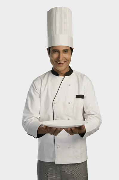 Chef holding a plate and smiling — Stock Photo, Image