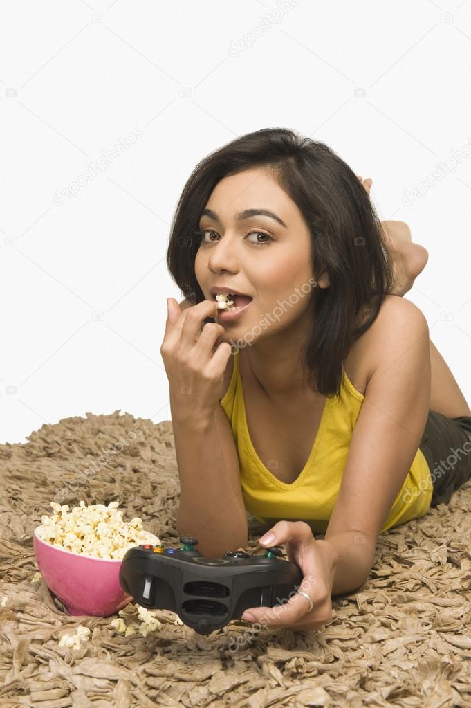 Woman eating popcorn and playing video game