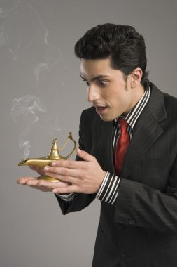 Businessman scratching a magic lamp clipart