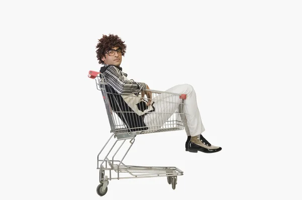 Homem sentado em um carrinho de compras — Fotografia de Stock