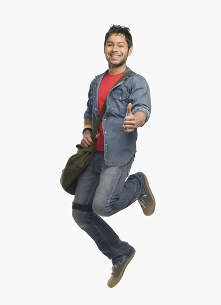 Student showing thumbs up and jumping — Stock Photo, Image