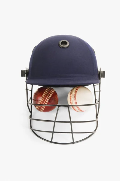 Bolas de cricket bajo un casco de cricket —  Fotos de Stock