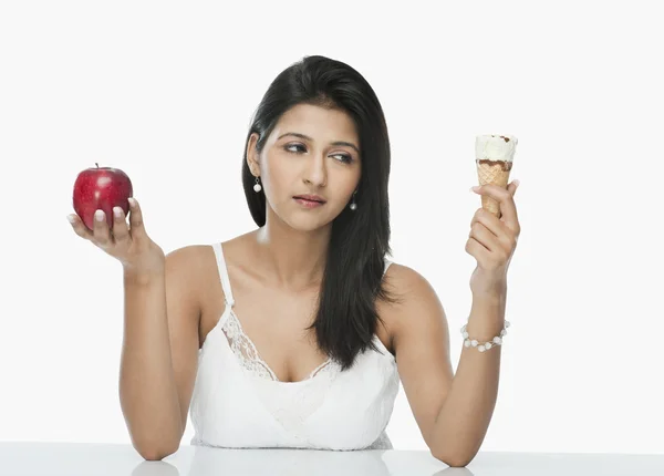 Mulher comparando um cone de sorvete com uma maçã — Fotografia de Stock