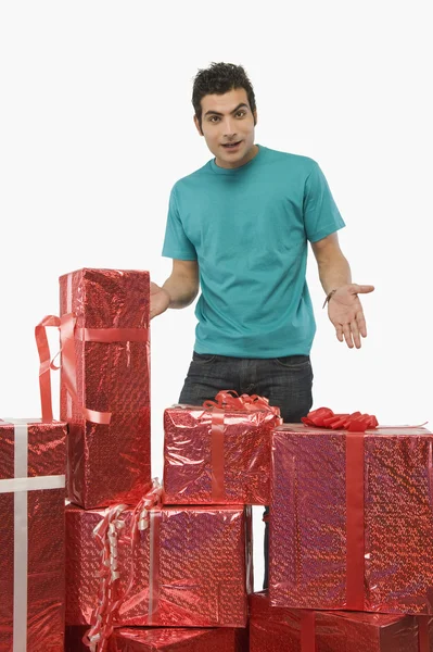 Man looking surprised behind gift boxes — Stock Photo, Image