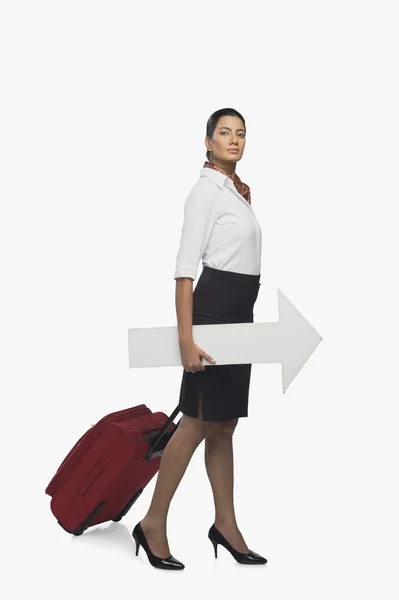 Air hostess carrying luggage with an arrow sign — Stock Photo, Image