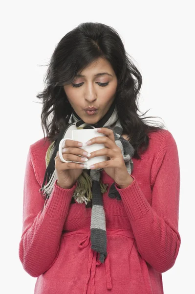 Woman blowing into a coffee cup — Stock Photo, Image