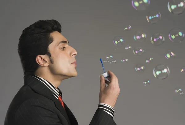 Businessman blowing bubbles — Stock Photo, Image