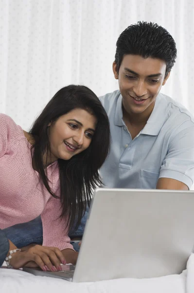 Couple using a laptop on the bed — Stock Photo, Image