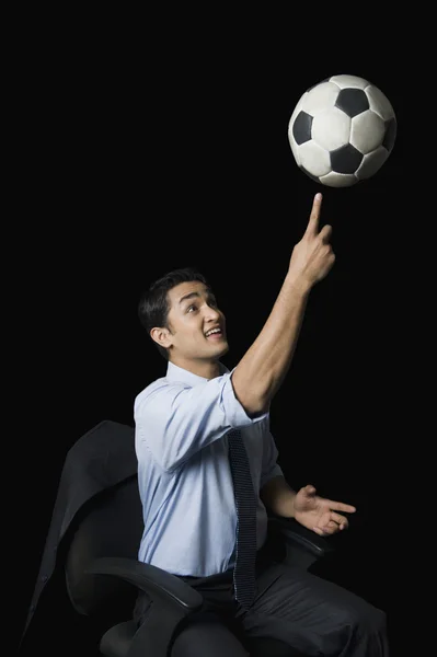 Businessman balancing a soccer ball on his finger — Stock Photo, Image