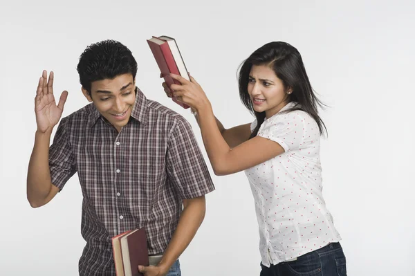 Mulher batendo seu amigo com um livro — Fotografia de Stock