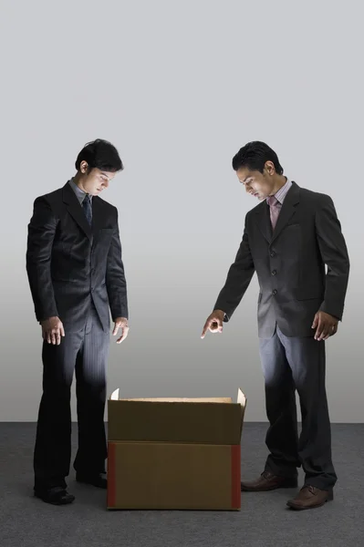 Empresários olhando para uma caixa de papelão iluminado — Fotografia de Stock
