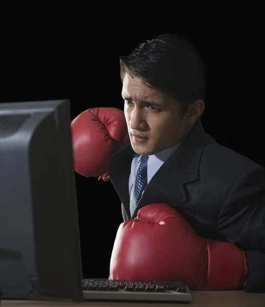 Businessman punching a desktop pc — Stock Photo, Image