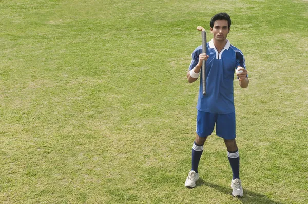 Hombre sosteniendo un palo de hockey en un campo — Foto de Stock