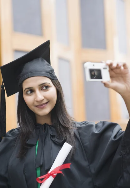 Woman in graduation gown taking a picture — Stock Photo, Image