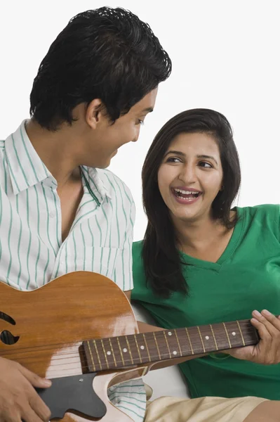 Man playing a guitar beside a woman — Stock Photo, Image