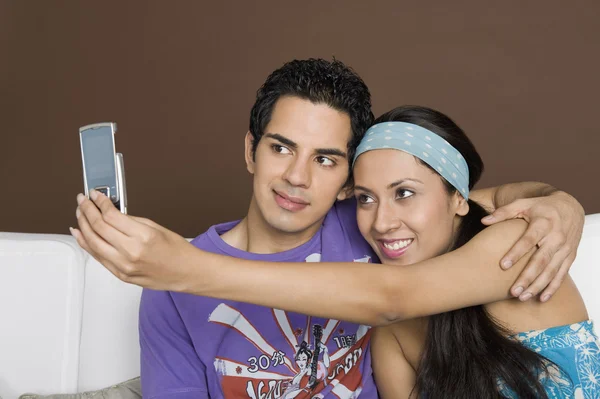 Casal tirando uma foto de si mesmos com um telefone celular — Fotografia de Stock