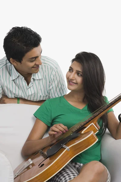 Mujer tocando una guitarra al lado de su novio — Foto de Stock