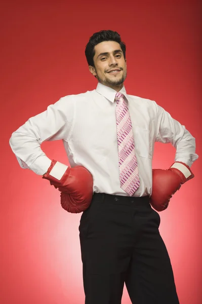 Businessman wearing boxing gloves and standing with arms akimbo — Stock Photo, Image