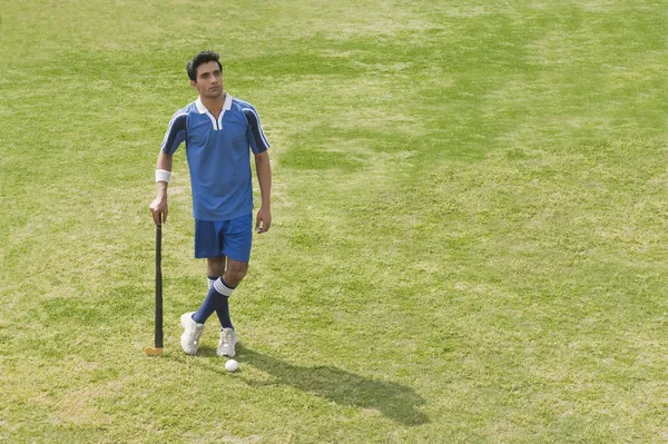 Man holding a hockey stick in a field — Stock Photo, Image