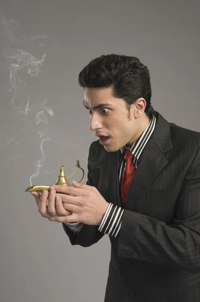 Businessman scratching a magic lamp — Stock Photo, Image