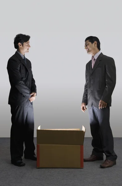 Des hommes d'affaires debout à côté d'une boîte en carton illuminée — Photo