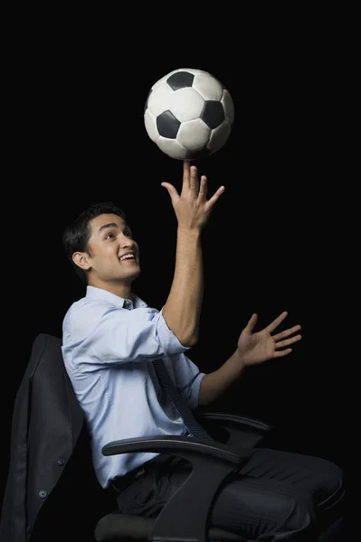 Businessman balancing a soccer ball on his finger — Stock Photo, Image