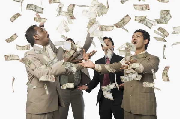 Billetes cayendo sobre cuatro hombres de negocios —  Fotos de Stock