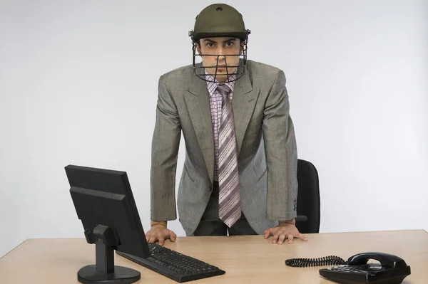 Uomo d'affari che indossa un casco da cricket e utilizza un computer — Foto Stock