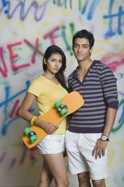 Couple standing with a skateboard — Stock Photo, Image