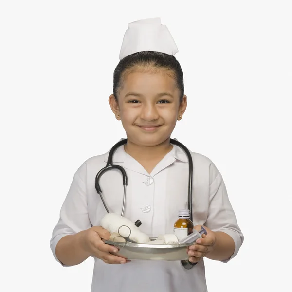 Menina vestida de enfermeira e segurando uma bandeja de medicamentos — Fotografia de Stock