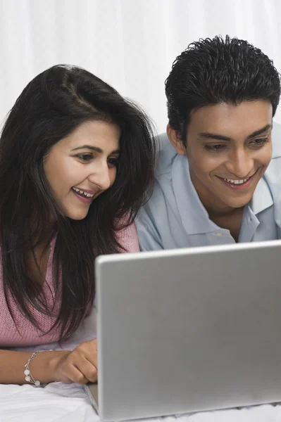 Casal usando um laptop na cama — Fotografia de Stock