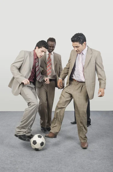 Empresários jogando com uma bola de futebol — Fotografia de Stock