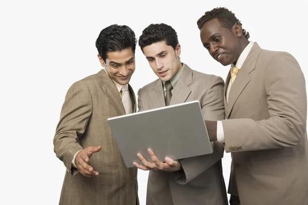 Drie zakenmensen die permanent met een laptop — Stockfoto