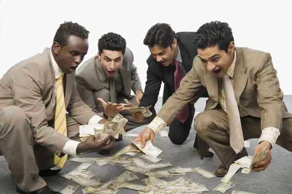 Podnikatelé krčí a držící bankovky — Stock fotografie