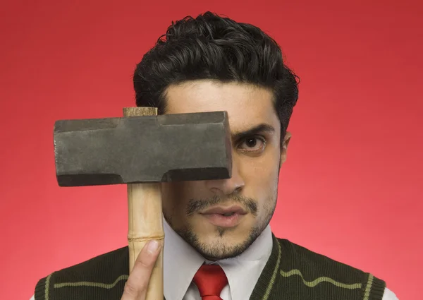 Empresario sosteniendo un martillo delante de su cara —  Fotos de Stock