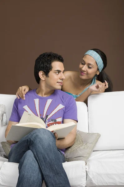 Hombre sosteniendo un libro y mirando a su novia — Foto de Stock