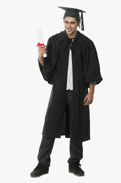 Man in a graduation gown holding a diploma — Stock Photo, Image