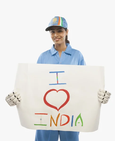 Femme en uniforme de cricket tenant une pancarte — Photo