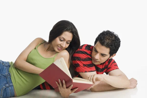 Couple lying on the floor and reading a book — Stock Photo, Image