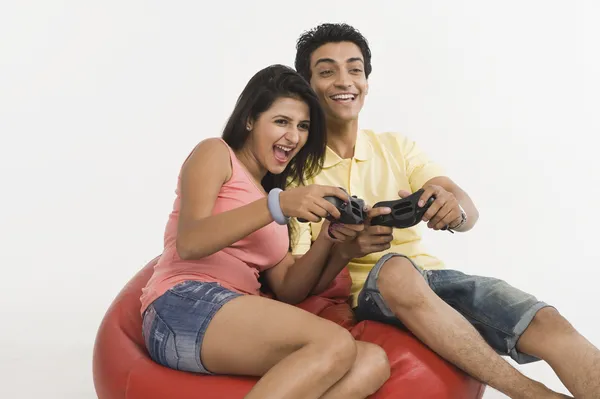 Пара, играющая в видеоигру на бобовом мешке — стоковое фото